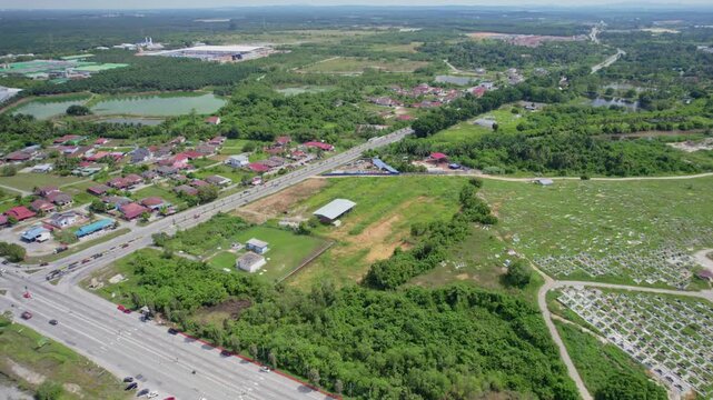 Wide aerial footage overlooking a highway network surrounded by green countryside, houses, farmland and developing rural areas in Malaysia.