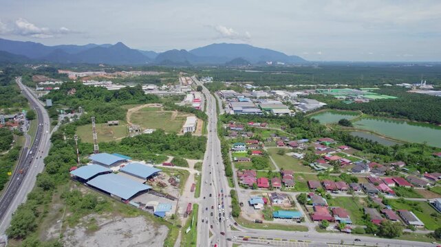 Expansive aerial view of Malaysian infrastructure showing parallel roadways connecting residential communities and industrial areas across a green developing landscape.