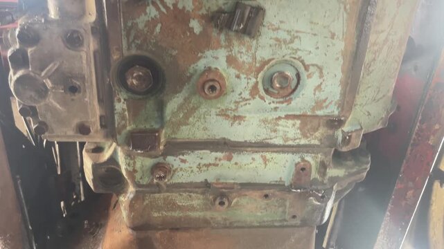 A close view shows the soiled underside of a heavy truck with rusted metal parts, grime, and water stains, highlighting detailed undercarriage cleaning during commercial vehicle maintenance.