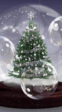 Animation of snow globe with christmas tree over christmas baubles decoration