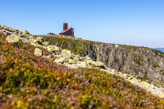 Horsk&aacute; bouda a vys&iacute;lač na okraji skaln&iacute; stěny Sněžn&yacute;ch jam v Krkono&scaron;&iacute;ch za slunečn&eacute;ho dne
Mountain hut and transmitter station on the edge of Sniezne Kotly glacial cirque in Krkonose Giant Mountains o