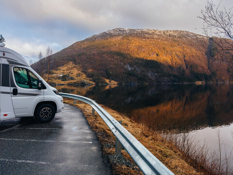 White camper van parked on scenic roadside viewpoint by a Norwegian fjord
