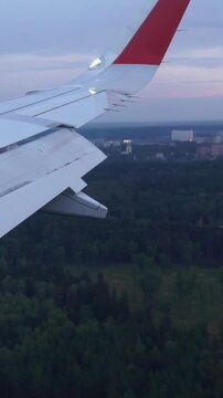 Airplane Wing Flying Over Forest and City Buildings