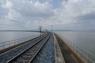 Fototapeta premium Railway track bridge over water, infrastructure beneath cloudy sky