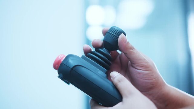 Hand holding black industrial remote control joystick device