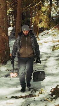 Lumberjack carrying axe and bucket in winter forest