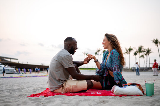 Casual young couple enjoying a spontaneous evening picnic on the sand focused on their relaxed style