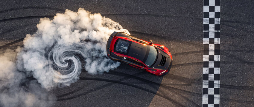 Sports car drifting on race track creating dense white tire smoke spiral near checkered finish line in top down aerial view for motorsport and automotive performance concepts