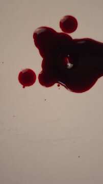 Blood dripping and impacting pool on light surface for crime scene evidence, top view slow motion, bottom copy space, vertical video