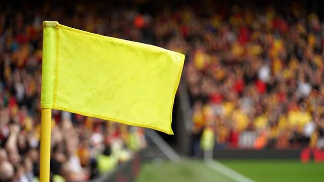 Yellow corner flag waving at a packed football stadium with blurred cheering crowd in background soccer