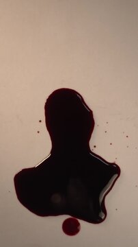 Blood dripping and accumulating into pool on off-white surface for forensic investigation, top view zoom in slow motion, top copy space, vertical video