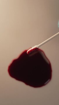 Close up of cotton swab collecting blood for crime scene investigation and lab testing, top view, blue gloved hand, vertical video