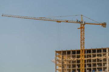 Construction crane towering over a new building project during a clear blue sky © beholdereye