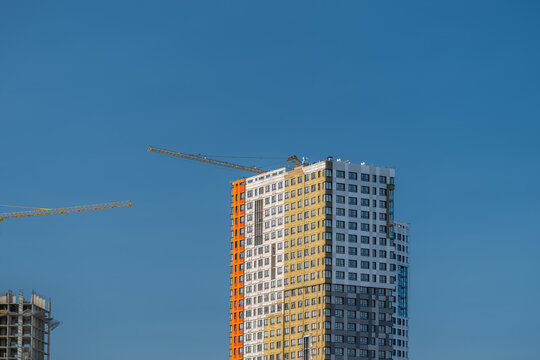 New building emerges against a clear sky cranes busy at work during midday construction in the heart of the city