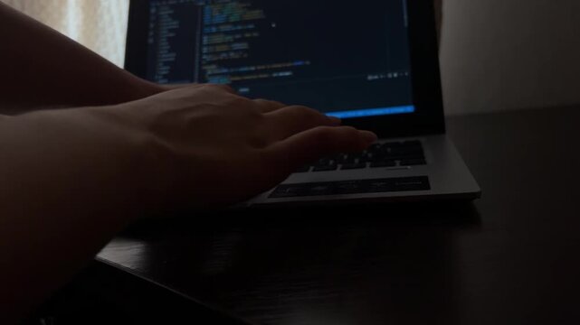 Professional programmer typing source code on a laptop keyboard in a dark office, focused on software development and debugging, a close up view of the cyber security process