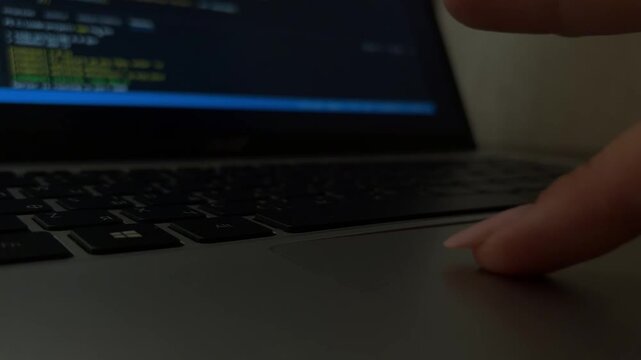 Young female hacker coding on a laptop in a dim room, close up on fast typing hands as a software developer writes code and scripts late at night, focused on the screen