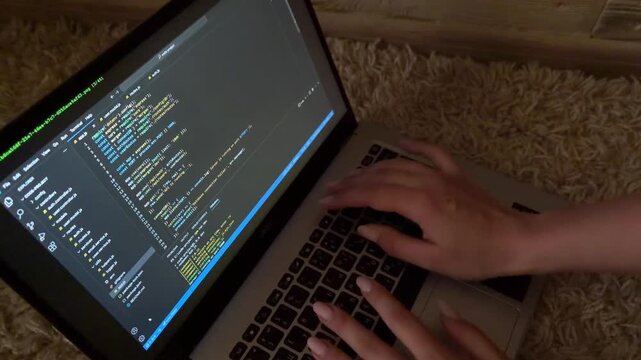 Female programmer's hands typing code on a laptop keyboard at night, close up view of software developing, website programming, and information technology concepts