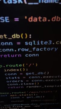 Close up view of scrolling lines of python code on a dark computer screen, showing functions and commands related to software development, programming, and web applications