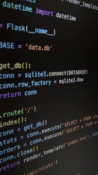 Python code scrolling on computer screen with syntax highlighting. A developer writing a program with a flask framework, connecting to a sqlite3 database for web development