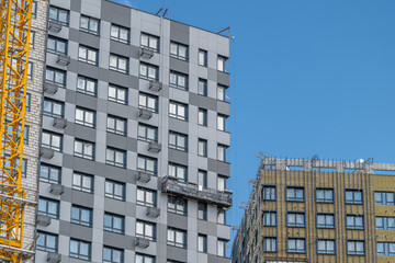 Construction workers scale new heights on a building in a bustling urban setting under a bright blue sky © beholdereye