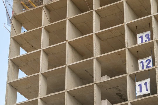 Construction of a high-rise building showcases rising concrete structure and numbered floors in a bustling city setting