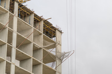 Construction site bustling with activity as the towering structure reaches for the sky under a cloudy gray sky © beholdereye