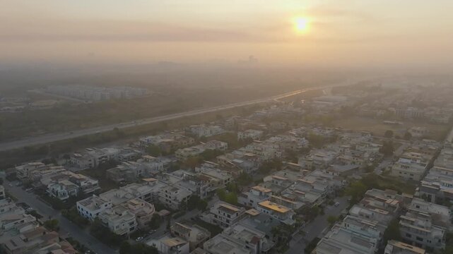Drone aerial view of residential houses and Margalla Road in Sector E-11 Islamabad at golden sunrise