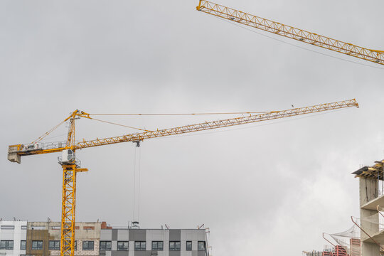 Construction cranes reach high against a gloomy sky in an urban setting showcasing the spirit of progress and development in the heart of the city