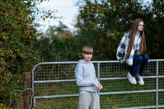 Teenagers siblings sitting on a fence in Ireland