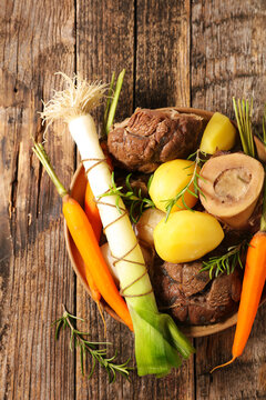 traditional french pot au feu with beef marrow bone leek carrots and potatoes on rustic wooden table