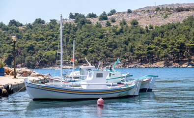 Traditional fishing boats moored in blue water at Lagkada Harbor, Ikaria Island, Greece © Rawf8