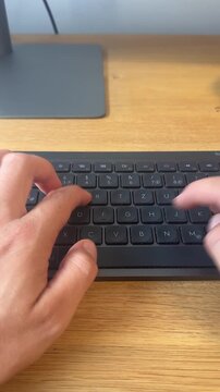 POV vertical video of hands typing fast on a slim wireless keyboard at a bright wooden home office desk, everyday remote work focus and digital productivity