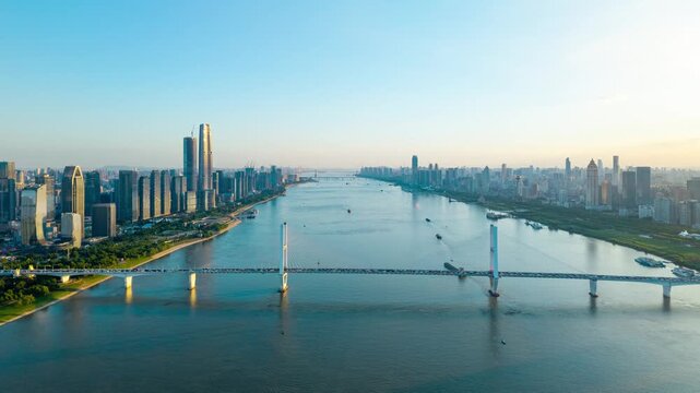 Aerial view of the modern city skyline and a large bridge spanning across the river in Wuhan China at sunset