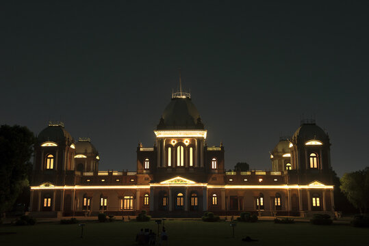 View of the illuminated Noor Mahal palace at night with its glowing windows and architectural domes in Bahawalpur, Punjab, Pakistan.