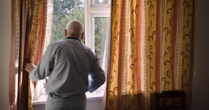 Curtains, window and view with senior man opening drapes after waking up alone in home. Wake up, morning sunshine and retired elderly male looking outside and getting ready for start of day in house.