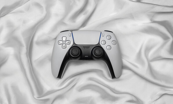 Modern white video game controller on folded silk fabric back