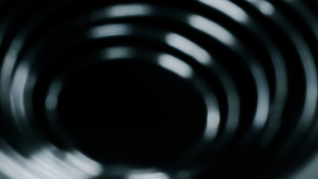 Abstract defocused dark background featuring blurred concentric rings and light reflections, creating a hypnotic tunnel or vortex effect.