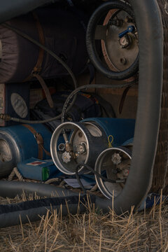 View of propane gas tanks and fuel hoses stored inside a wicker hot air balloon basket on dry grass in Gravina in Puglia, Apulia, Italy.