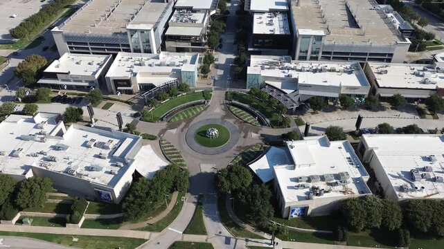 Curved entrance rotary anchors commercial retail plaza near Warren Parkway along Platinum Corridor. Multi level garages border landscaped drives throughout corporate district, Frisco, Texas