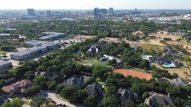 Sprawling tree canopy shields residential estates before distant skyline across North DFW suburbs. Corporate complexes meet shaded neighborhoods across thriving suburban Frisco, Texas