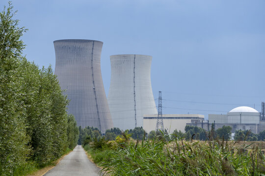 View of the Doel Nuclear Power Plant with its cooling towers rising above the surrounding greenery and a rural path in Beveren-Kruibeke-Zwijndrecht, Vlaanderen, Belgium.
