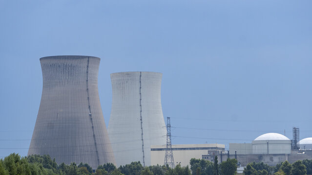 View of the cooling towers and reactor buildings at the Doel Nuclear Power Plant under a clear blue sky in Beveren-Kruibeke-Zwijndrecht, Vlaanderen, Belgium.