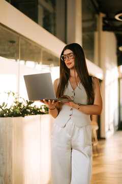 Businesswoman working on a laptop in a modern office at sunset