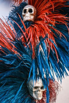 View of decorative skulls adorned with vibrant red and blue feathers, representing traditional Dia de los Muertos festivities in Oaxaca, Oaxaca, Mexico.