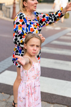 A mother and daughter gesture with confusion while standing near a crosswalk in Paris. The tourists try to figure out directions while walking along a city street.