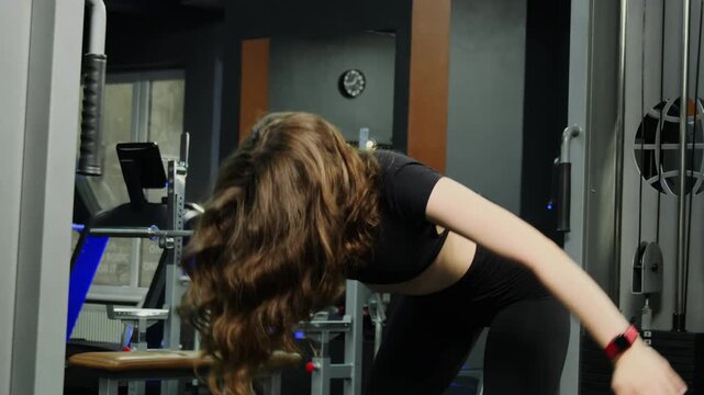 Woman performs windmill exercise during gym mobility training. Young athlete rotates torso reaching one arm upward with steady balance in gym