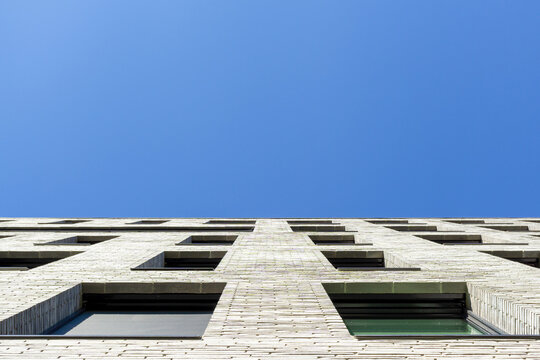 Modern brick building facade reaching clear blue sky