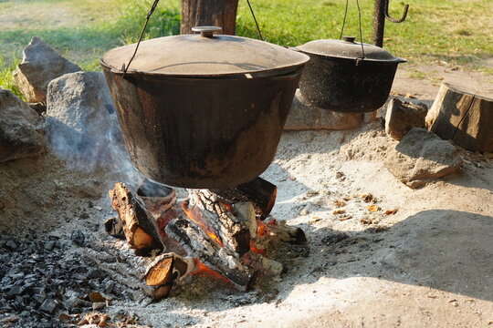 Cast iron cauldron cooking over open campfire flames outdoors