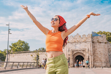Young woman raising arms, feeling happy and free while exploring historical Nis Fortress in Serbia...