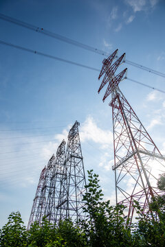 View of high-voltage transmission towers at Bonneville Dam with steel lattice structures and power lines against a clear blue sky in Cascade Locks, Oregon, United States.